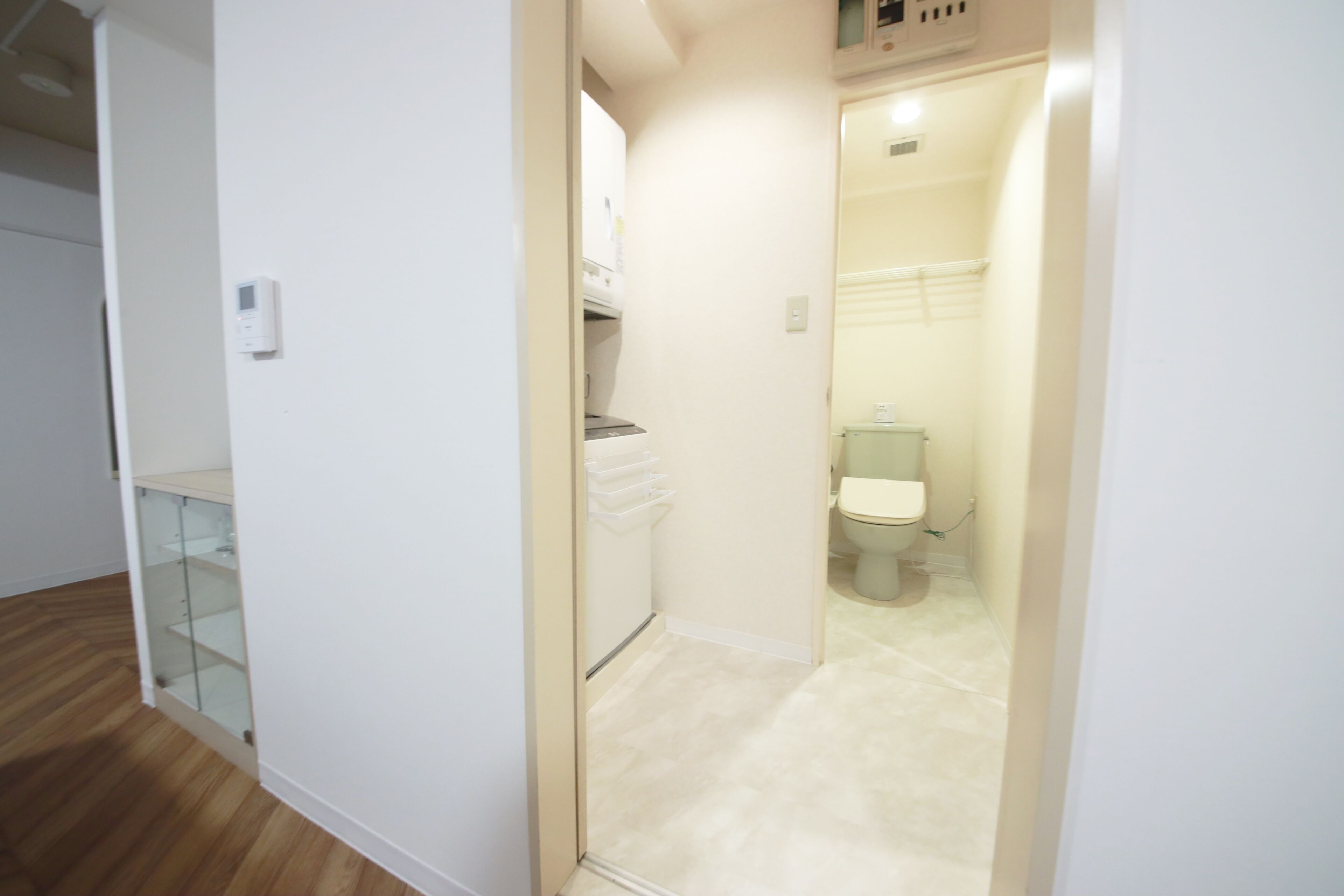 A hallway leading to a bathroom with a toilet and a shower area.