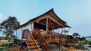 A wooden house with a porch and staircase, surrounded by tropical plants. - ShriGo Resort Pushkar (Peesangan)