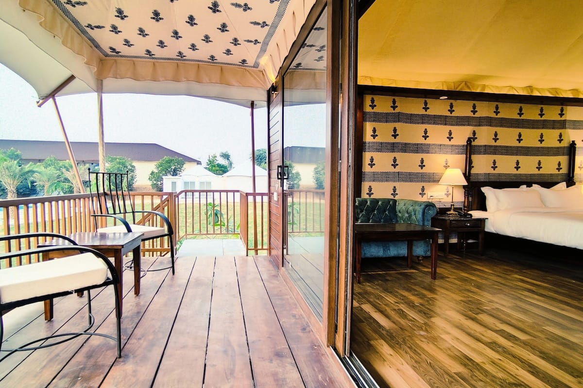 A balcony with a wooden floor, a table, and two chairs.