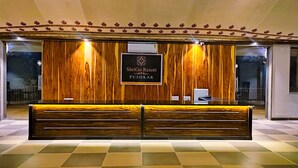 A reception desk with a wooden finish, a sign for ShriGo Resort Pushkar, and an air conditioning unit above it. - ShriGo Resort Pushkar (Peesangan)