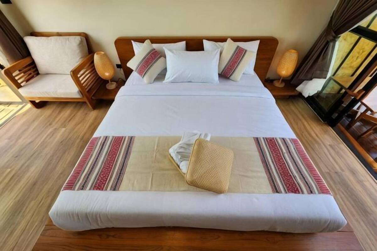 Una habitación de hotel con una cama grande, una silla de madera y una mesita.