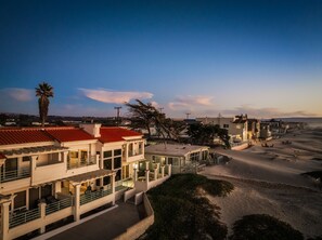 A coastal residential area with houses featuring red-tiled roofs and a sandy beach. - Strandcastle Beach House - Oceanfront! - You're right on the sand! (Oceano)