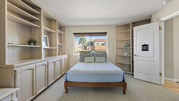 A bedroom with a bed, built-in shelving, a wardrobe, and a door with a sign.
