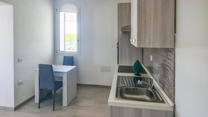 Une cuisine de taille réduite avec une fenêtre, une table à manger avec des chaises et un évier.