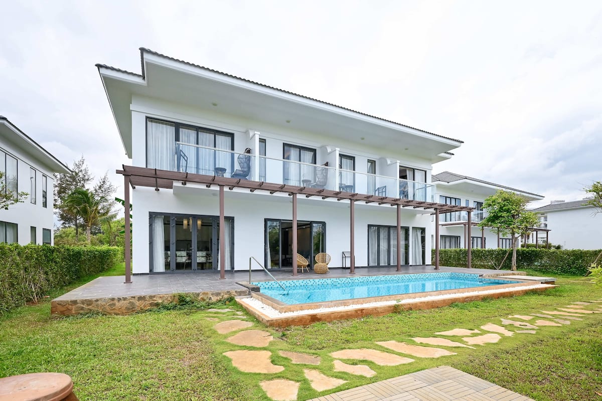 A modern two-story house with a swimming pool, large windows, and a covered patio area.
