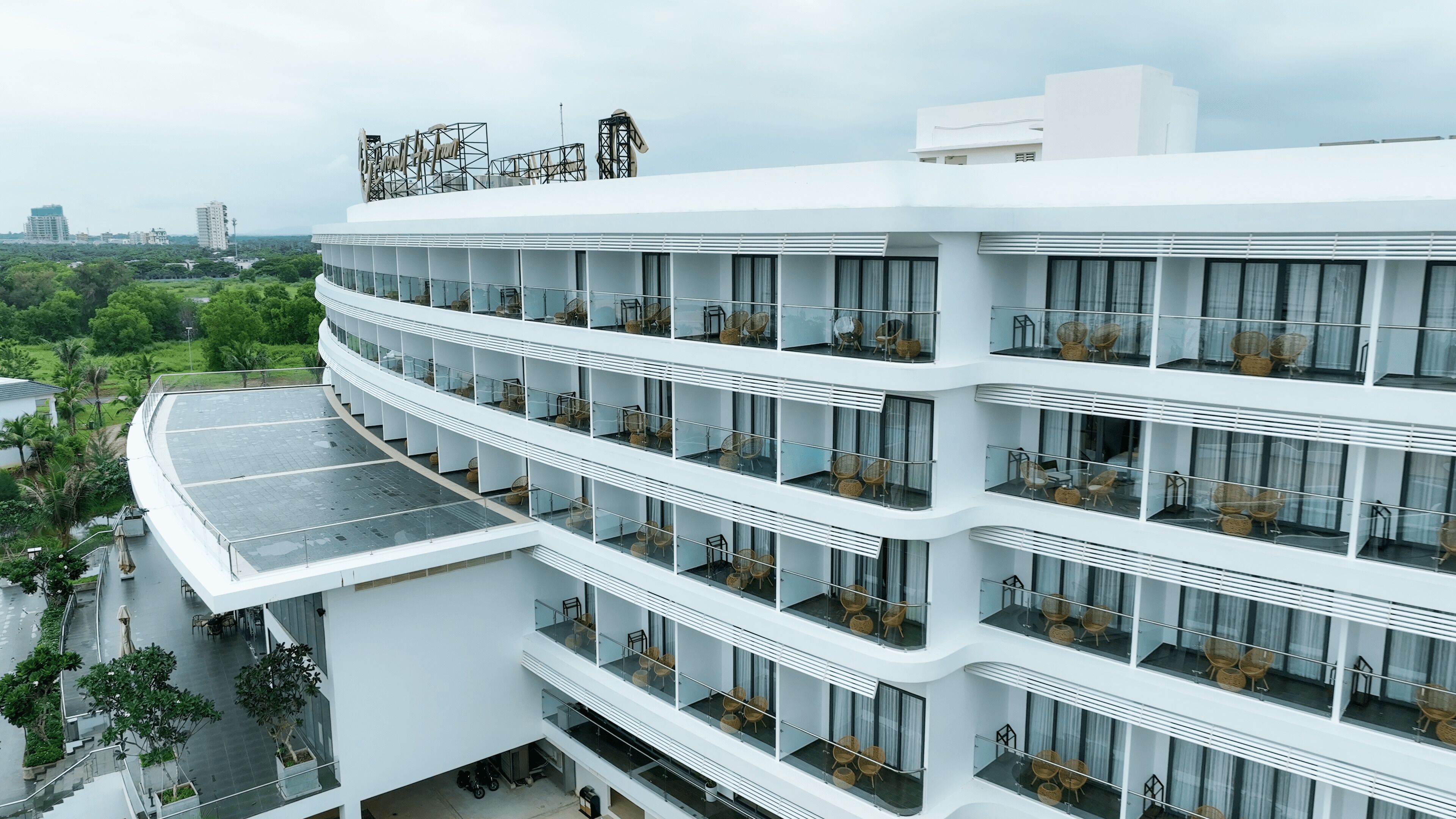 Un hotel de varios pisos con balcones, ventanas amplias y una terraza en la azotea.