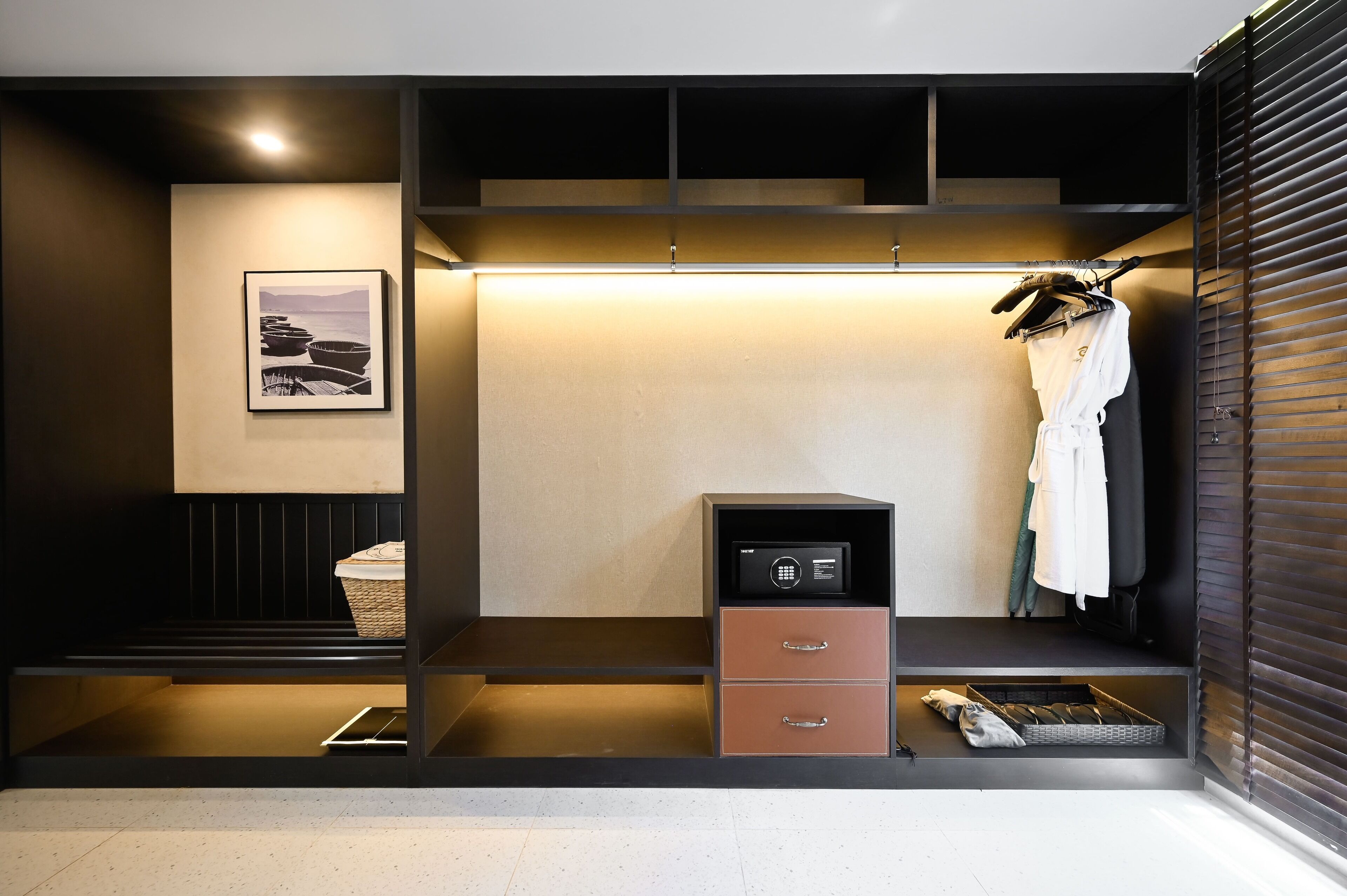 A modern, well-lit walk-in closet with a secure safe, a hanging rack, and a framed picture on the wall.