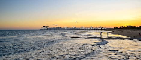 A pier extending into the ocean with waves gently lapping at its base.