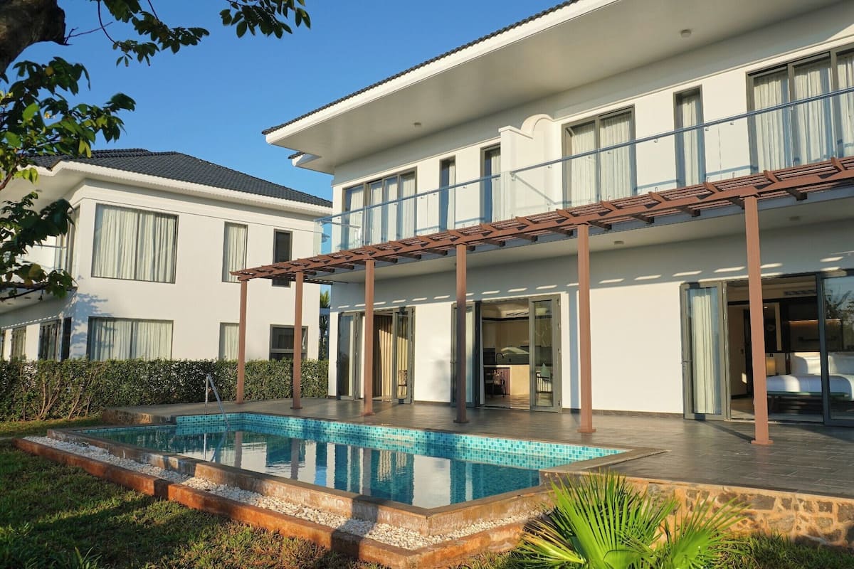 A modern two-story house with a swimming pool, large windows, and a covered patio area.
