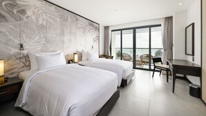 A hotel room with two beds, a desk, and a view of the outdoors. - Emerald Ho Tram Resort (Ho Chi Minh City)