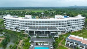A large, multi-story hotel with a circular layout, featuring a central courtyard with a swimming pool and outdoor seating. - Emerald Ho Tram Resort (Ho Chi Minh City)