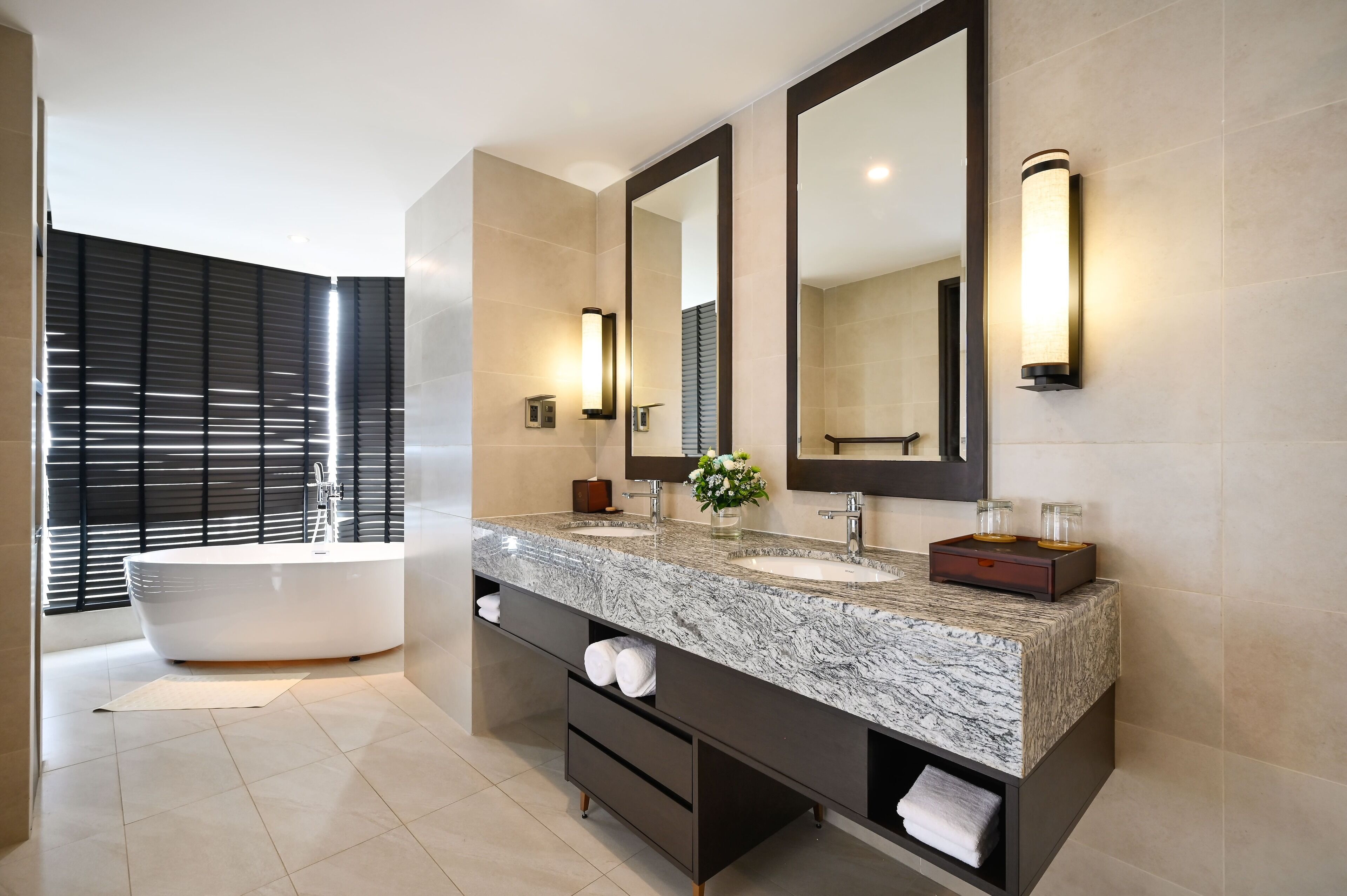 A modern bathroom with a freestanding bathtub, a large vanity with a marble countertop, and a large mirror.