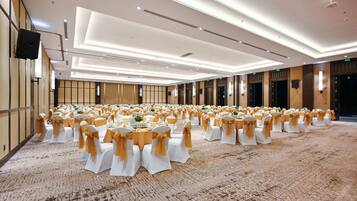 A large banquet hall with rows of tables and chairs, each with white tablecloths and gold sashes.