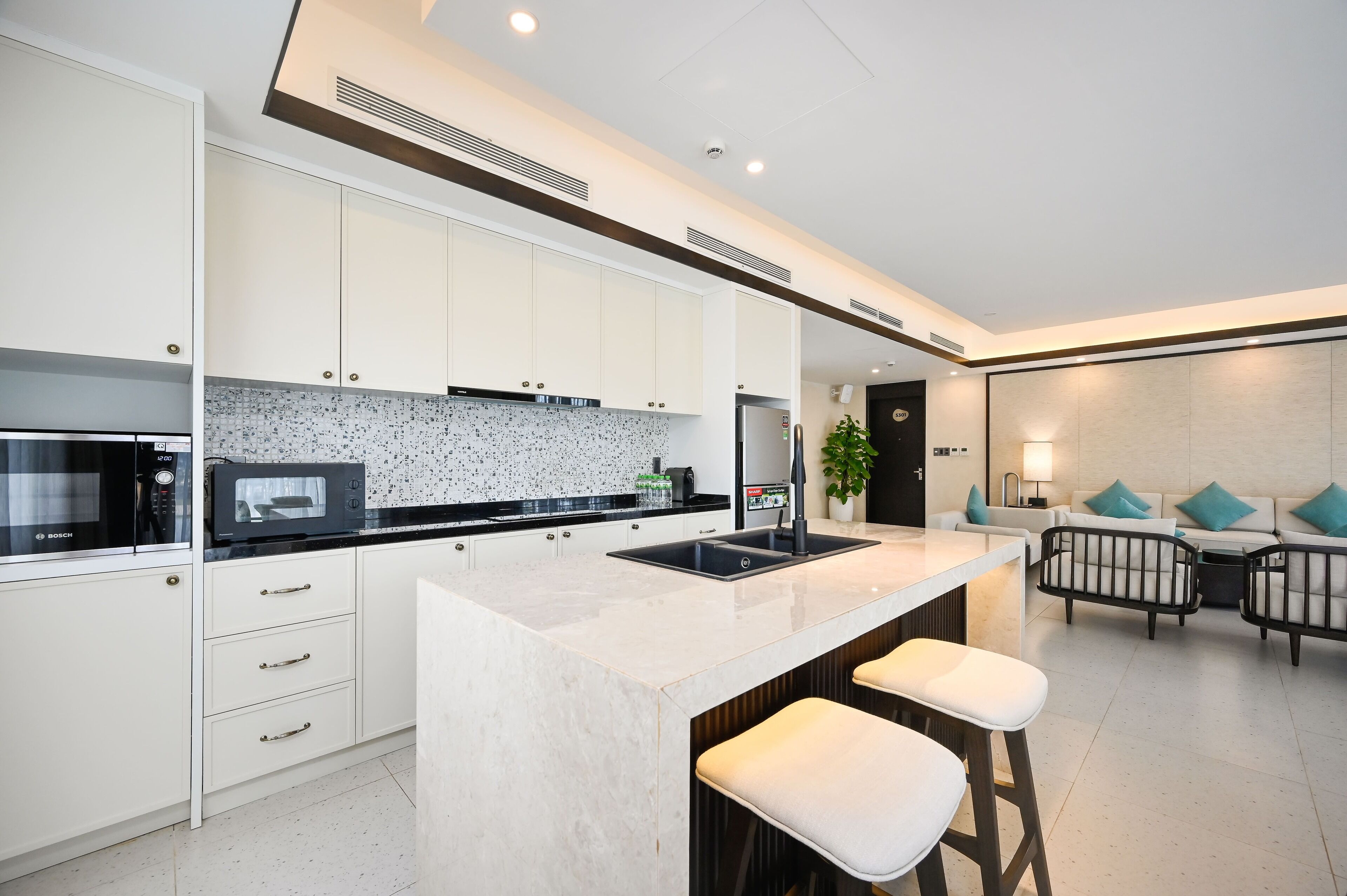 Una cocina moderna con armarios blancos, encimera negra y una isla integrada con taburetes de bar.