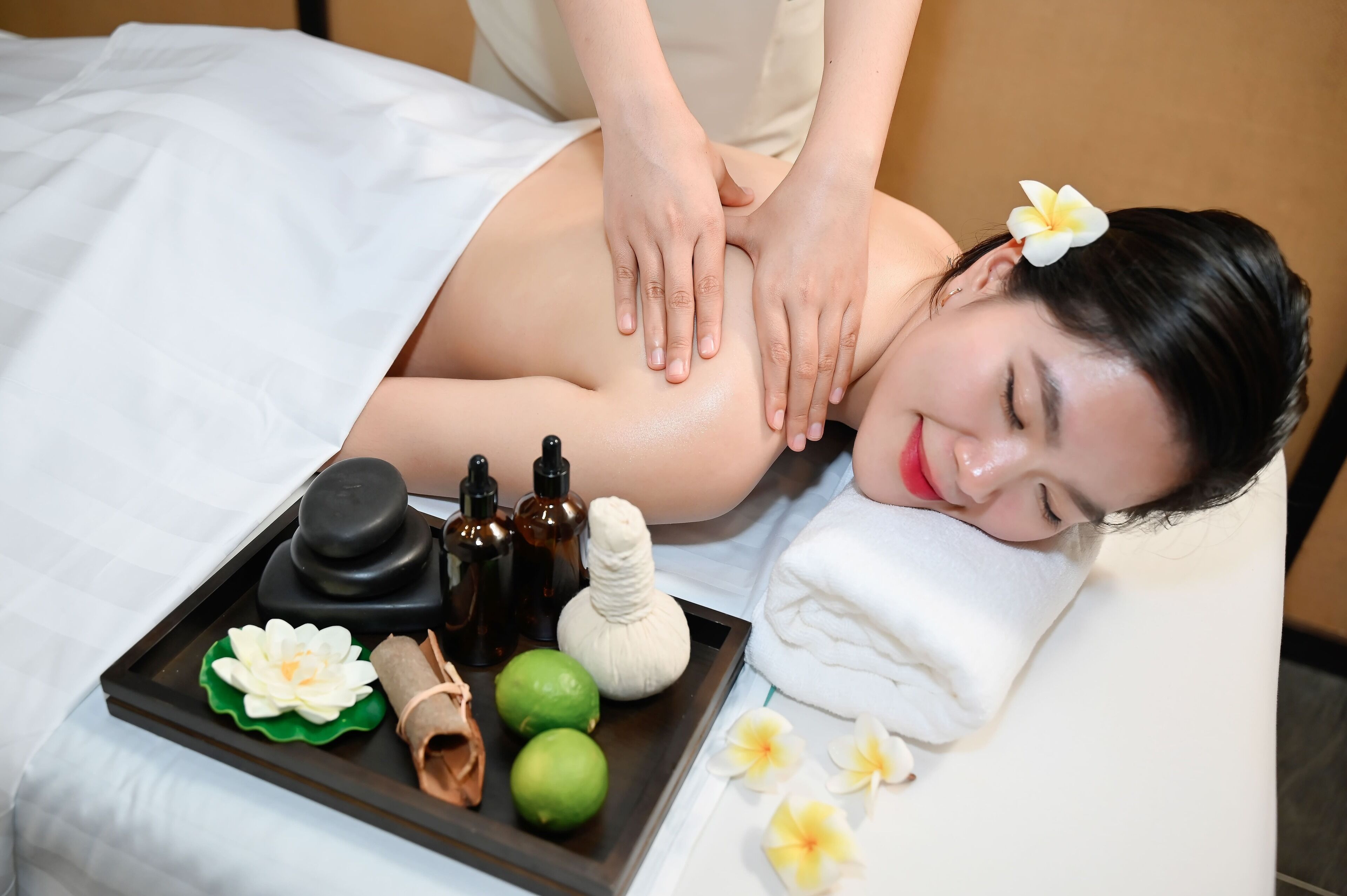 Een massage sessie met een dienblad vol massagemiddelen en een witte handdoek.