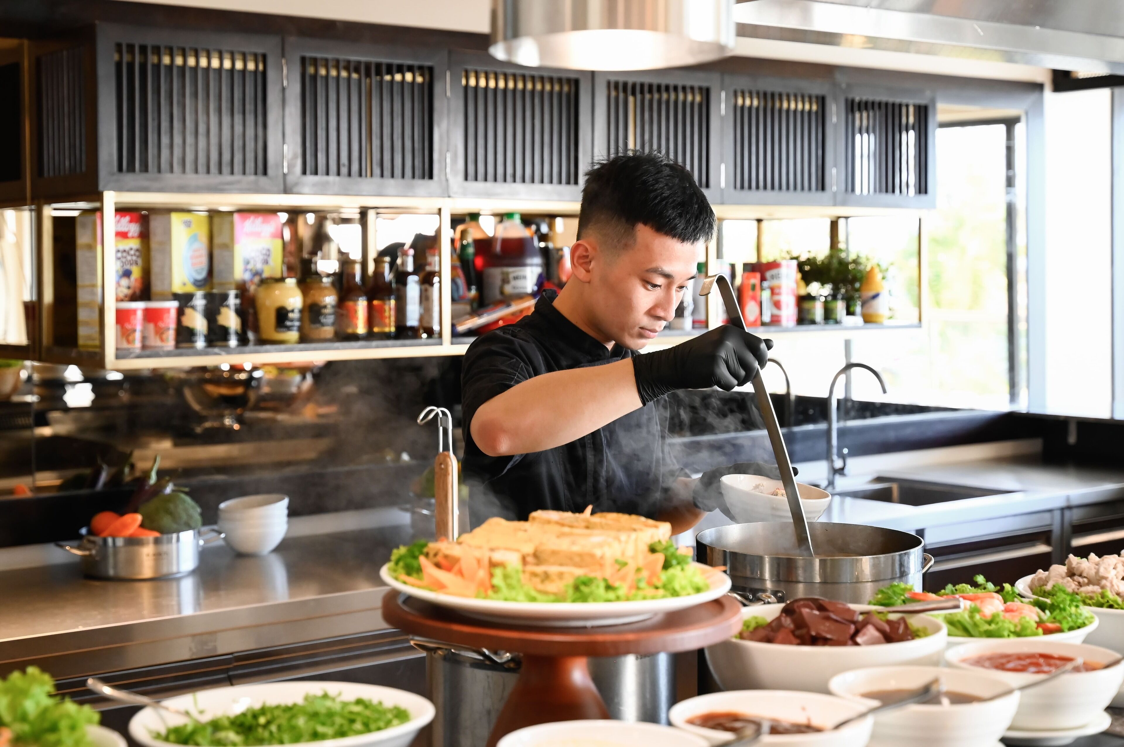 A chef preparing food at a hot plate station in a restaurant.