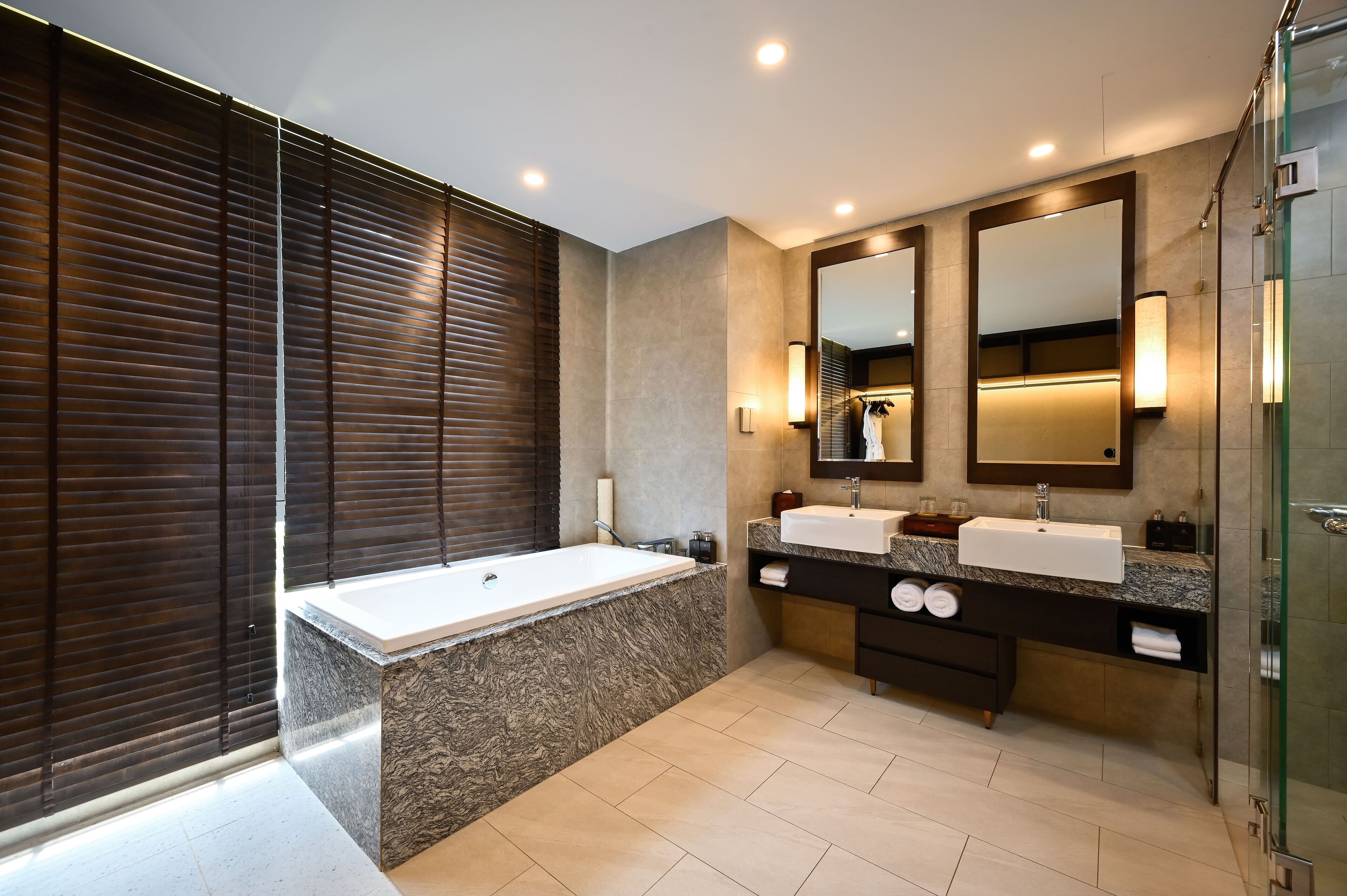A modern bathroom with a large bathtub, two sinks, and a glass shower enclosure.