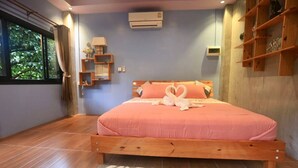 Un dormitorio con una cama de madera, una ventana con cortinas, un aire acondicionado instalado en la pared y una estantería con objetos decorativos.