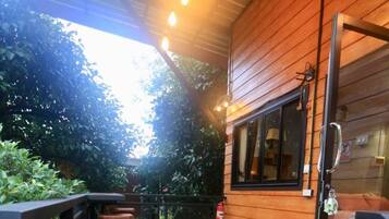 An outdoor patio with hexagonal tiles, wooden walls, and a seating area with chairs and a table.