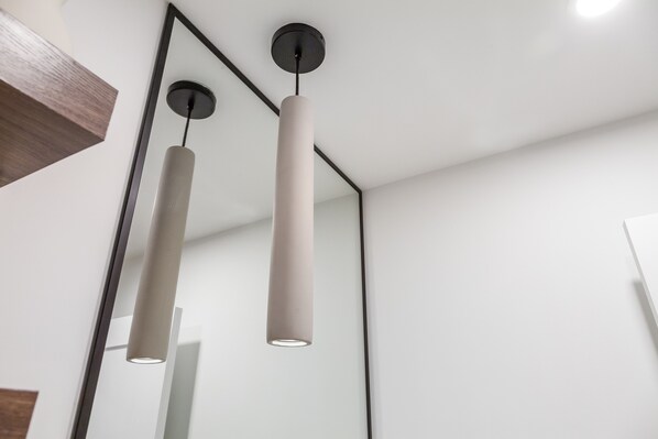 A modern interior with minimalist pendant lighting and a reflective wall. - New, Modern & Clean Luxury Studio Suite - Great Location! (Burnaby)