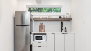 Een moderne keuken met een roestvrijstalen koelkast, een magnetron en witte kasten.