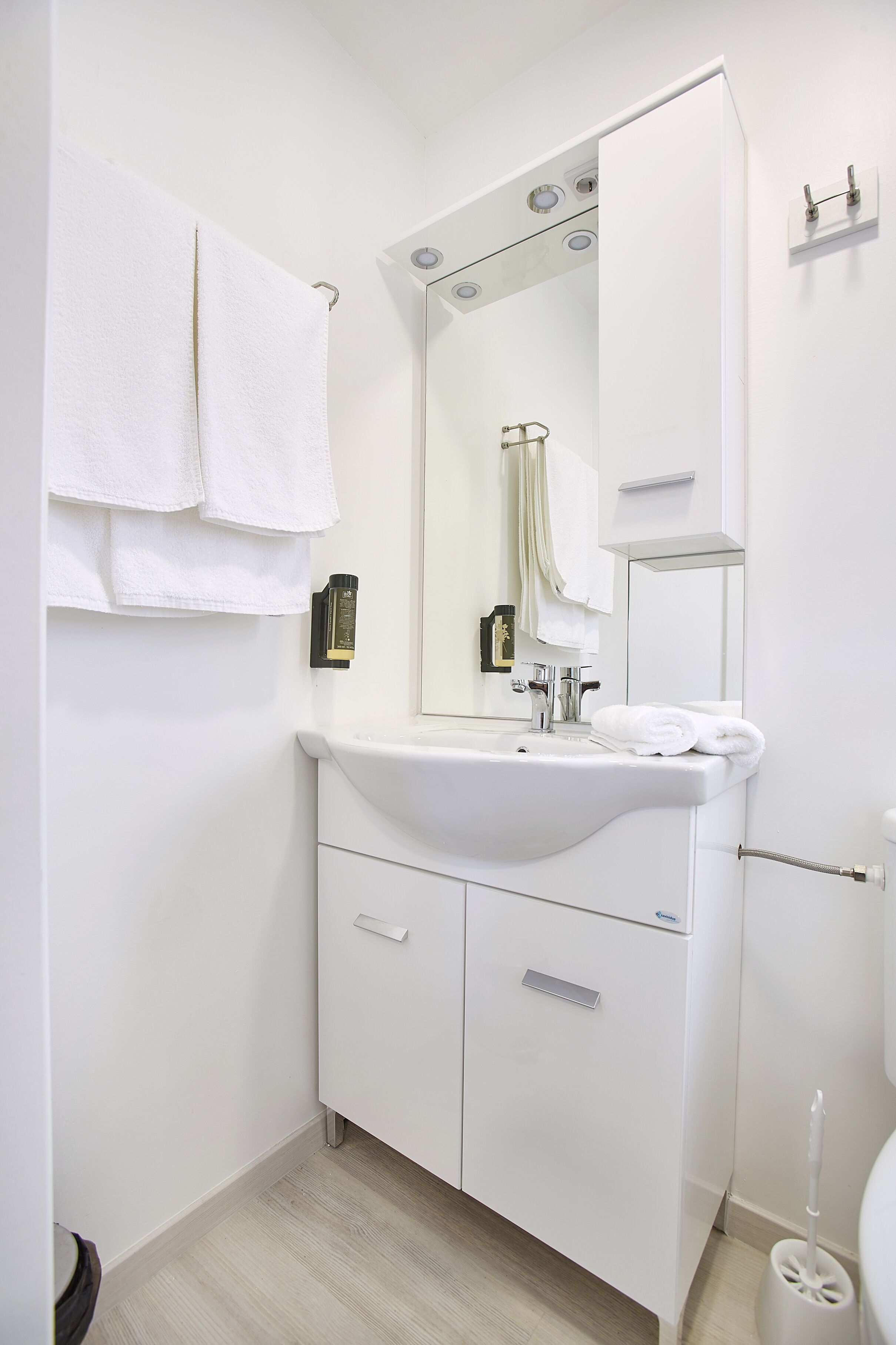 Une salle de bain avec un lavabo blanc, un miroir et deux serviettes accrochées au mur.