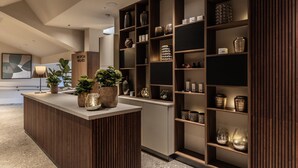 Zona de recepción con un mostrador de madera, plantas en macetas y estantes con objetos decorativos.