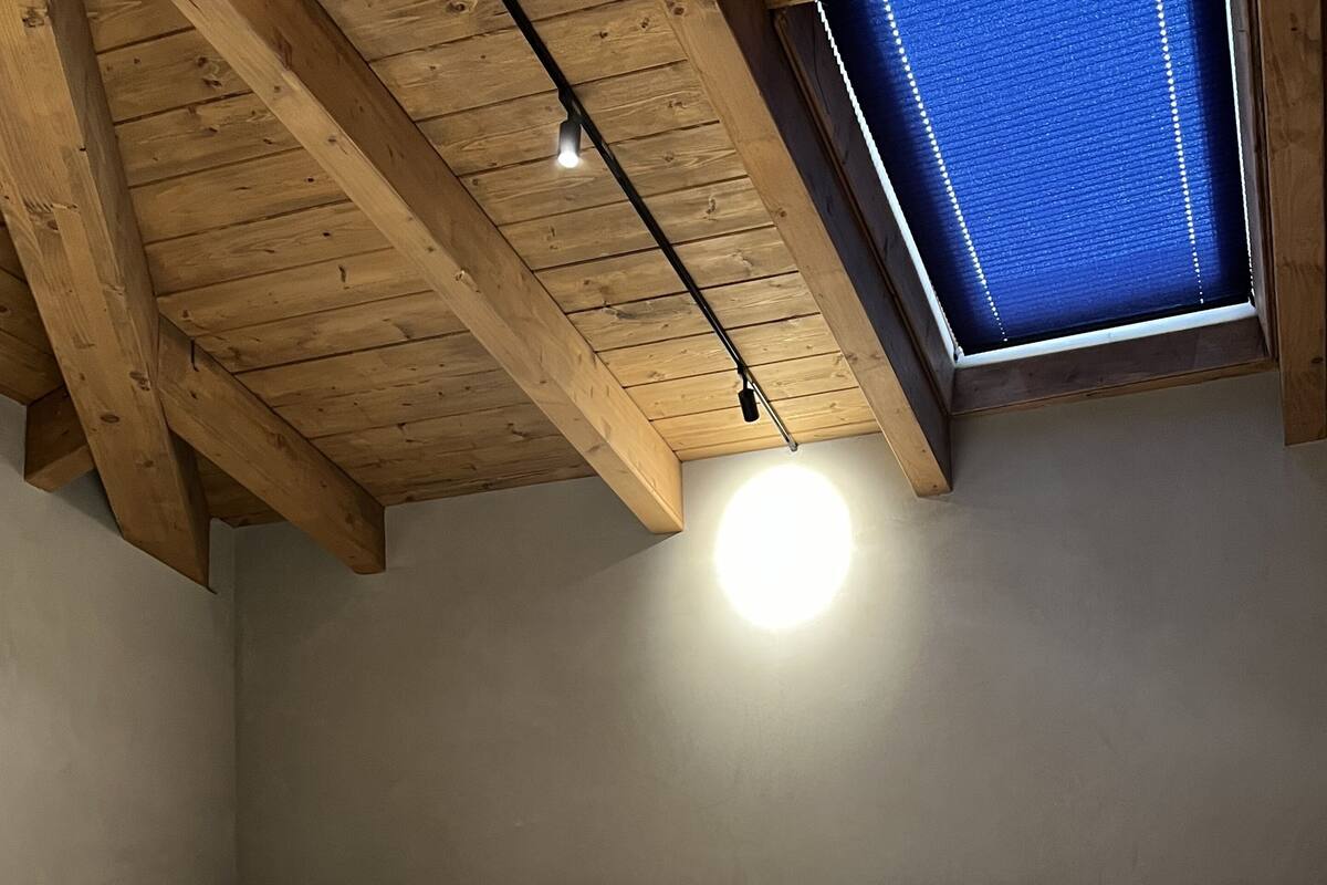 Une chambre  à coucher avec un cadre de lit en bois, un puits de lumière et un seul luminaire.