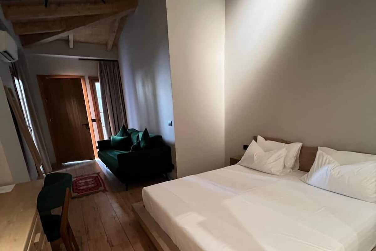 Une chambre avec un grand lit, un plancher en bois et un canapé vert.
