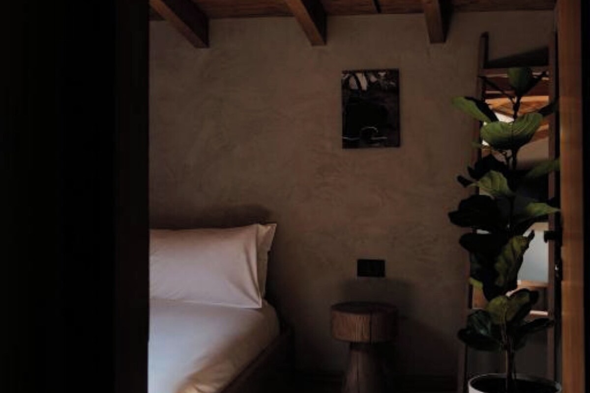Ein gemütliches Schlafzimmer mit Holzbalkendecke, einem Bett, einem kleinen runden Tisch und einem Topf mit Pflanze.