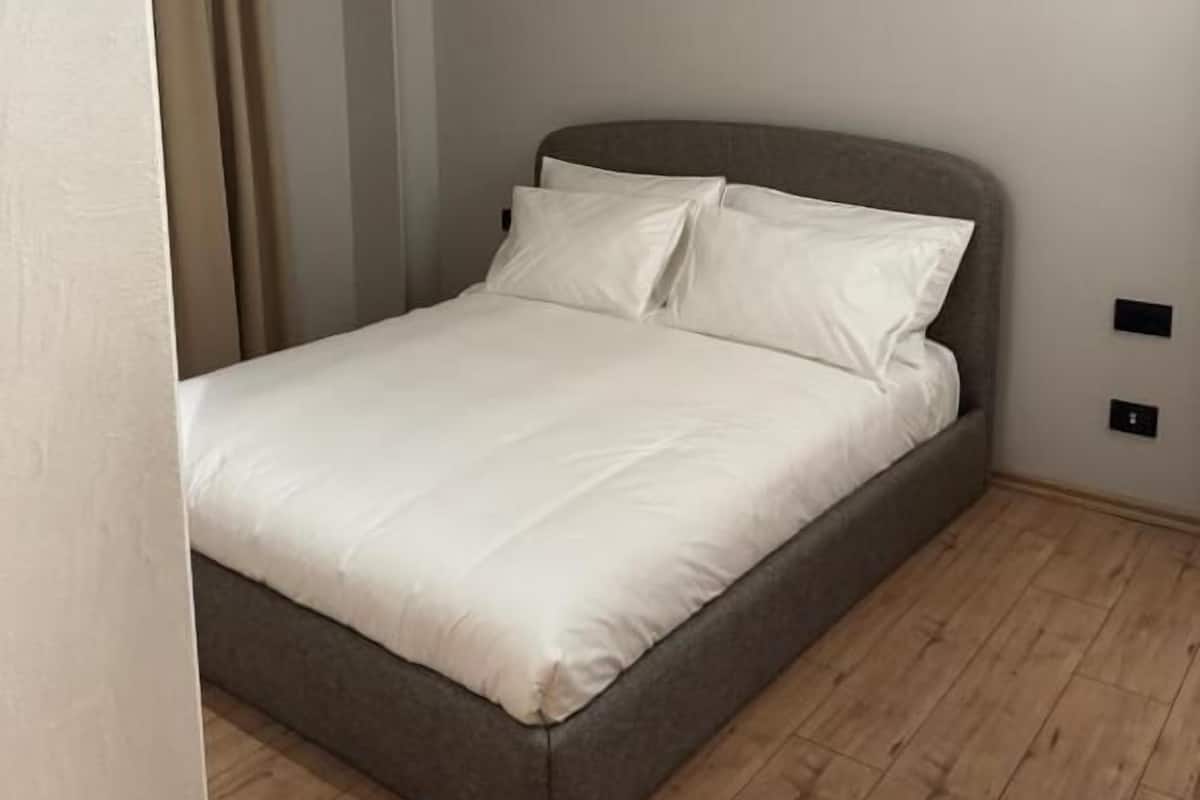Une chambre à coucher avec un lit, un plancher en bois et un rideau.