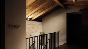 Un escalier avec un plafond en bois et un mur en briques, menant à une pièce sombre.