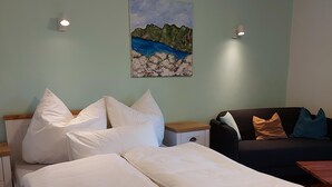 A bedroom with a bed, a nightstand, a dresser, a couch, and a painting on the wall. - Ferienwohnung 1 für Max. 2 Personen (Ruhpolding)