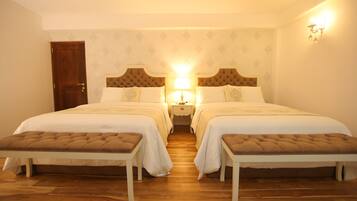 A double room with two beds, a bench, a nightstand, and a wall-mounted lamp.