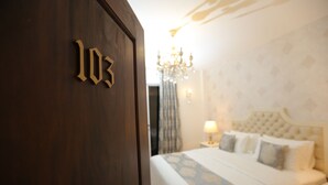 Una habitación de hotel con una cama grande, un candelabro y una puerta con el número 103.
