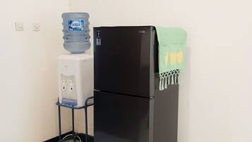 Een zwarte koelkast met een groene handdoek erboven, een waterdispenser en een witte drinkwaterkoeler.