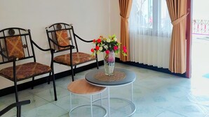 A room with two chairs, a small table, and a vase with flowers. - Penginapan Prambanan TRISAN (Prambanan)