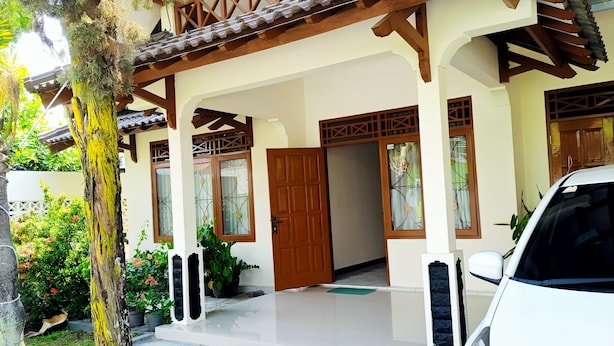 A traditional house with a tiled roof, wooden pillars, and a front door. - Penginapan Prambanan TRISAN (Prambanan)