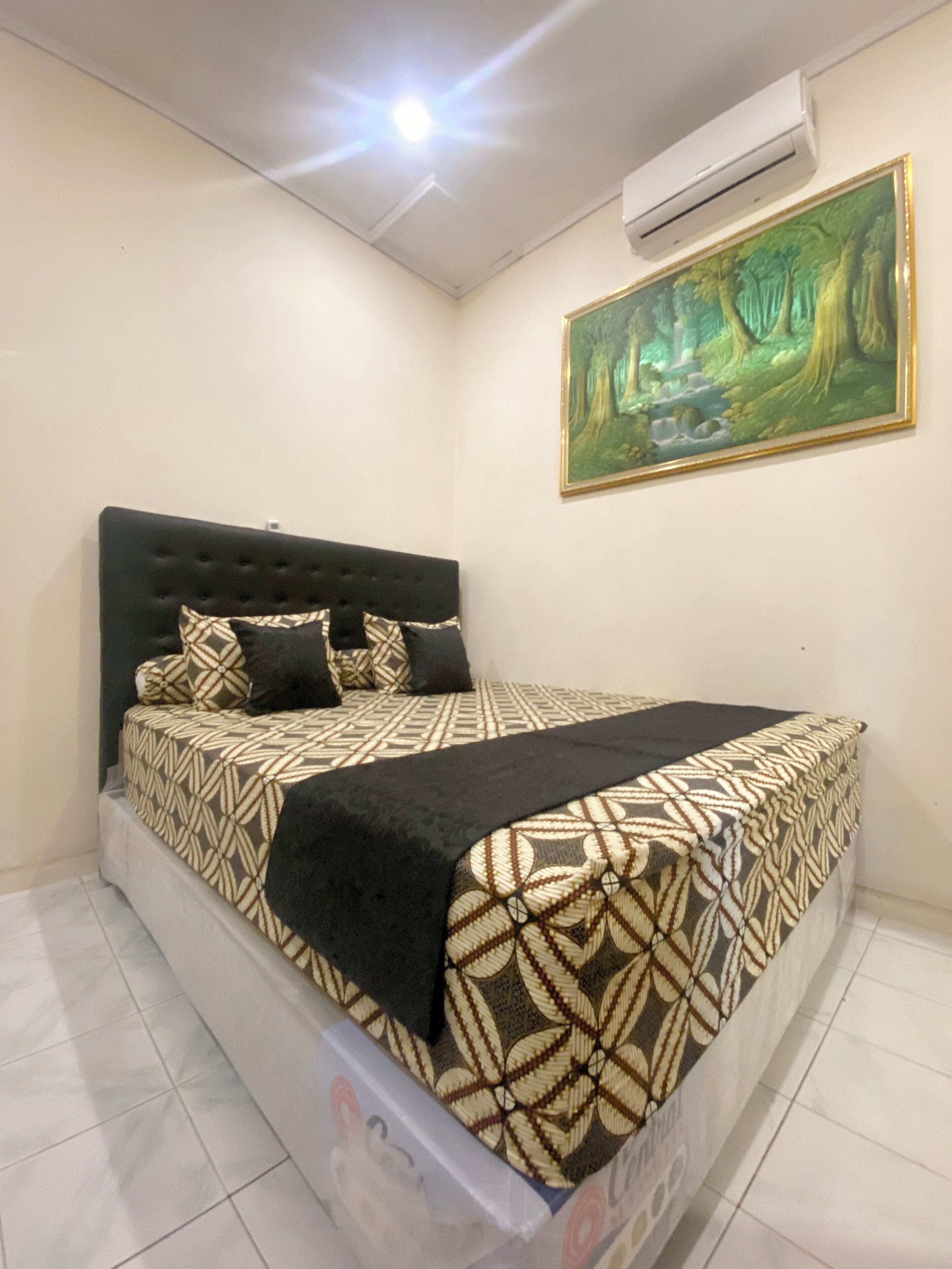 Una camera da letto con un letto, un quadro e un condizionatore.