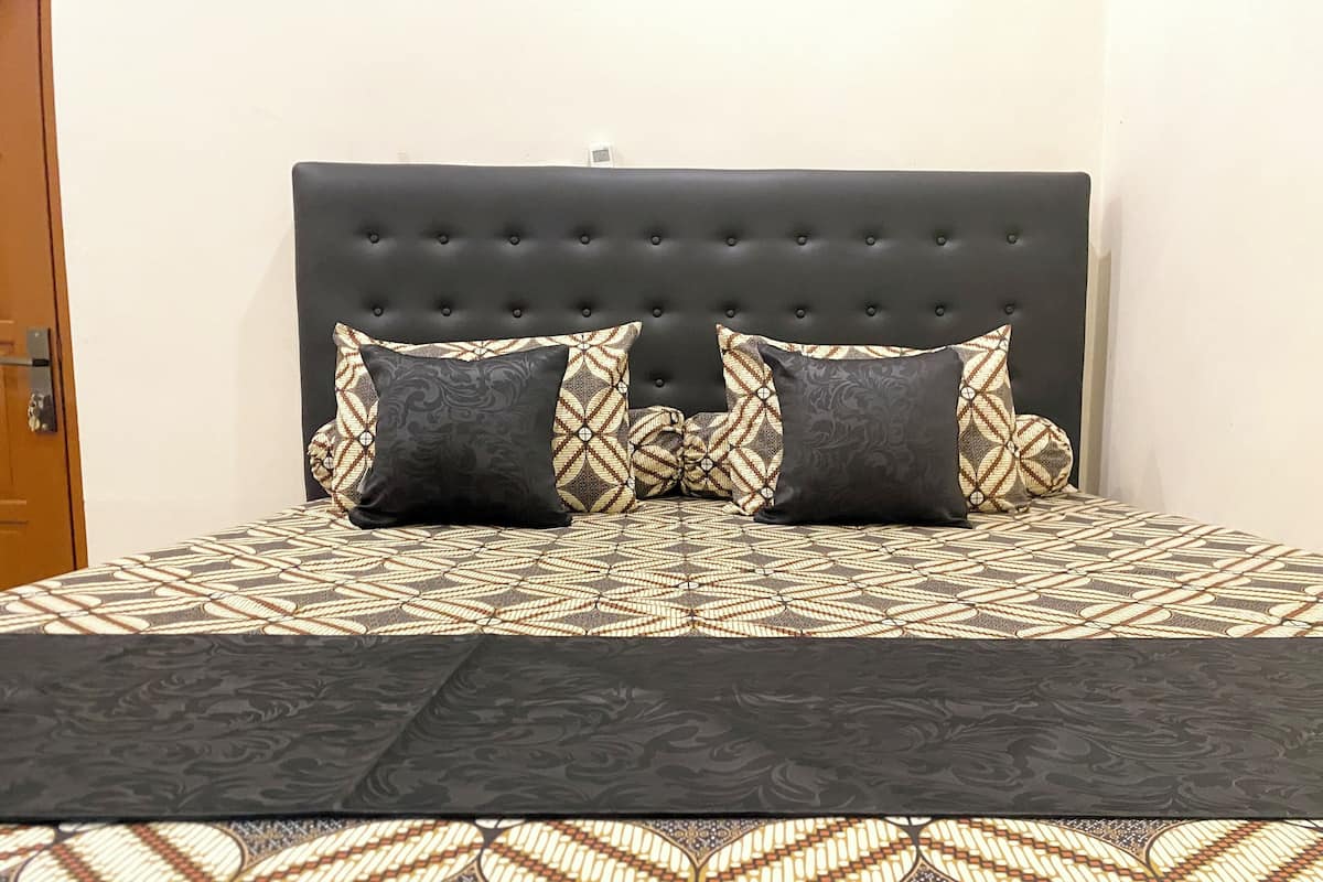 A bed with a patterned bedspread and two square pillows.