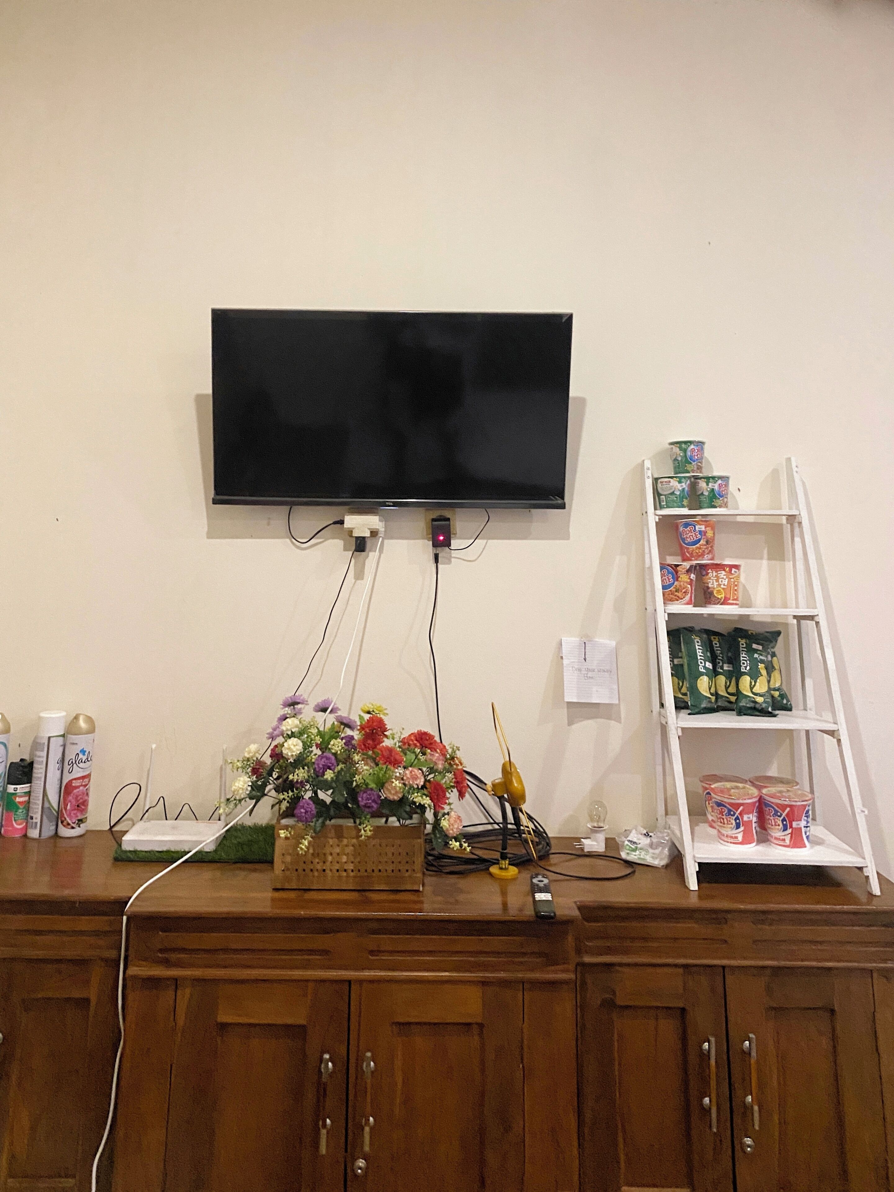 Een flatscreen televisie bevestigd aan een muur, verbonden met een houten kastje eronder.