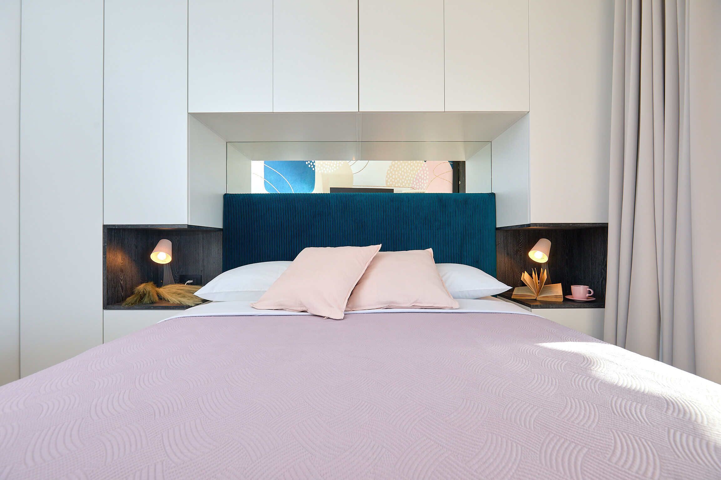 Un dormitorio moderno con una cama grande, dos mesitas de noche y un diseño de cabecera original.
