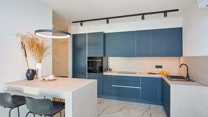A modern kitchen with blue cabinets, a marble countertop, and a black faucet. - Hedera Estate, Hedera A45 (Dubrovnik)