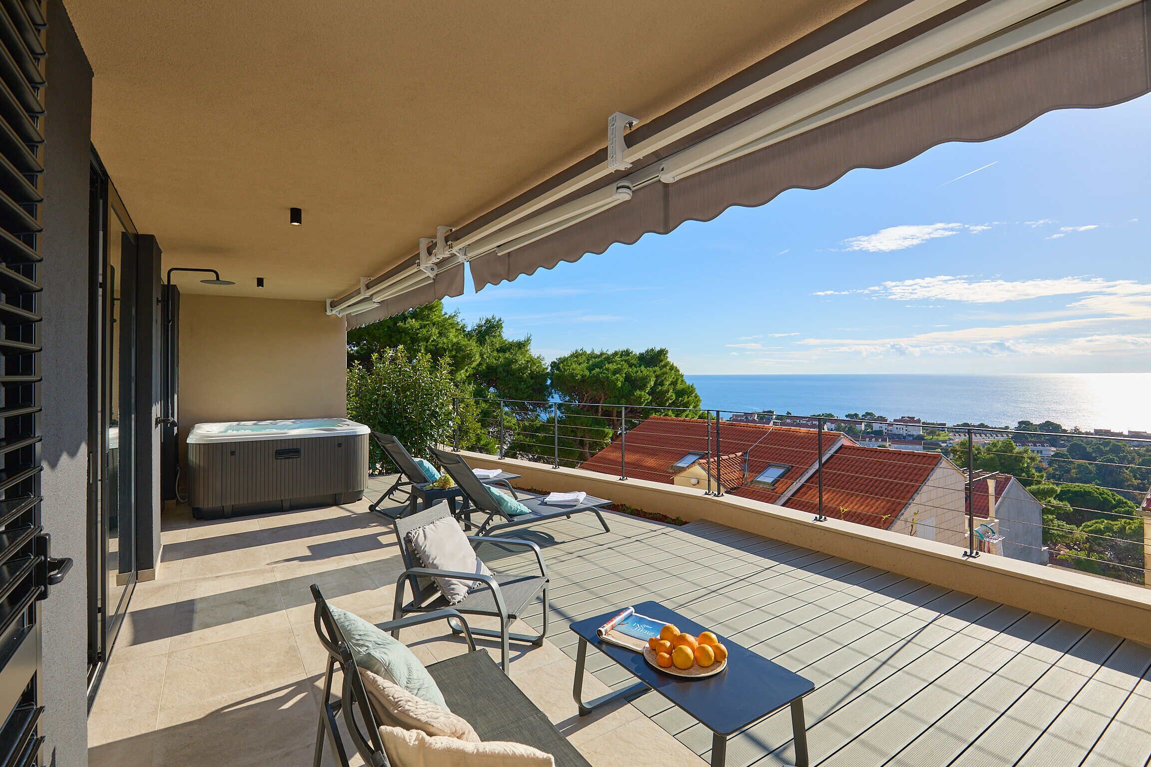 Un balcon avec un jacuzzi, des chaises longues et une table avec des oranges.