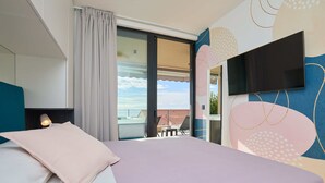 A hotel room with a bed, a TV mounted on the wall, a window with curtains, and a view of the outside. - Hedera Estate, Hedera A45 (Dubrovnik)