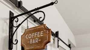 A kitchen with a coffee bar setup, including shelves with coffee-making equipment and a hanging sign that reads "COFFEE BAR".