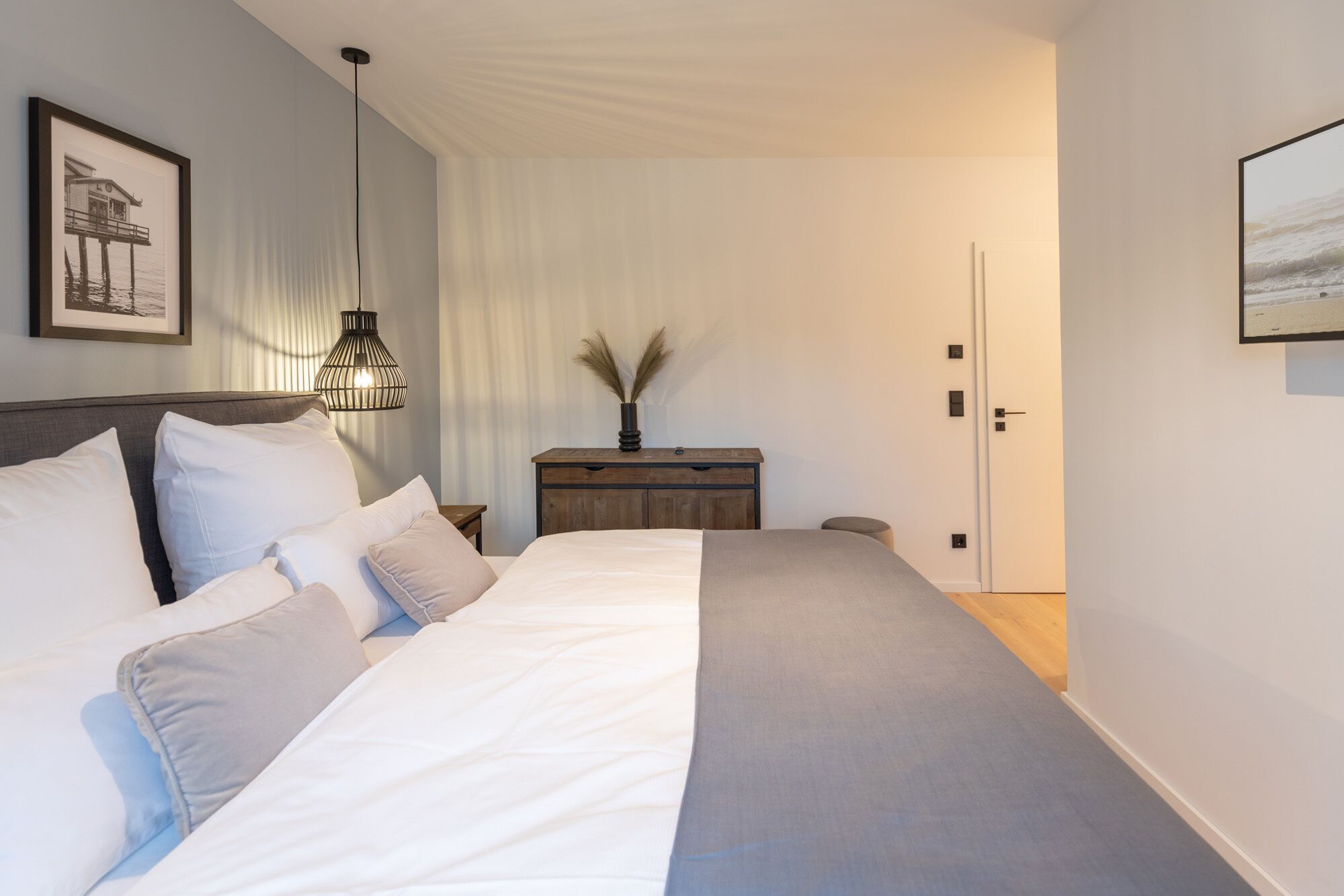 Ein Schlafzimmer mit Bett, Nachttischen, einer Kommode und einer Tür.