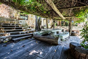 A stone staircase leading up to a wooden deck with a mosaic bench and a tree trunk. - Wonderland Cape Town (Cape Town)