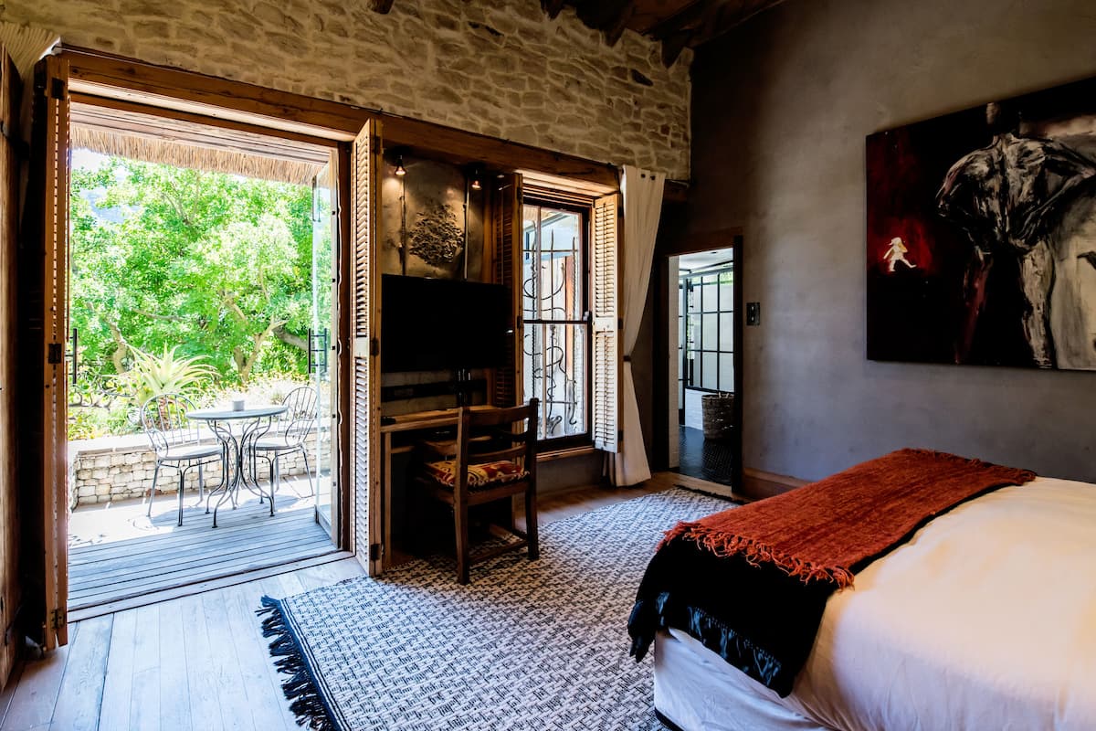 Ein Schlafzimmer mit einem Bett, einem Schreibtisch und einem Stuhl nahe eines großen Fensters.