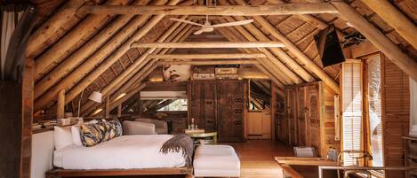 A rustic wooden room with a loft bed, a small desk, and a cowhide rug.